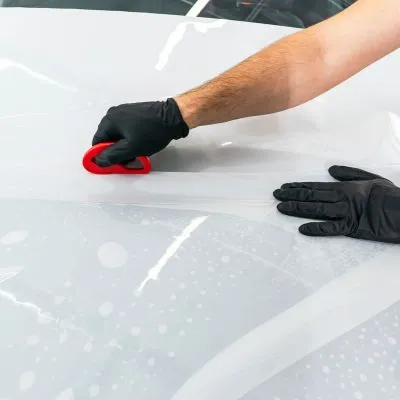 Persona aplicando vinilo blanco en coche